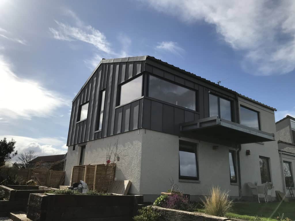 Modern residential architecture with black metal facade and spacious balcony.