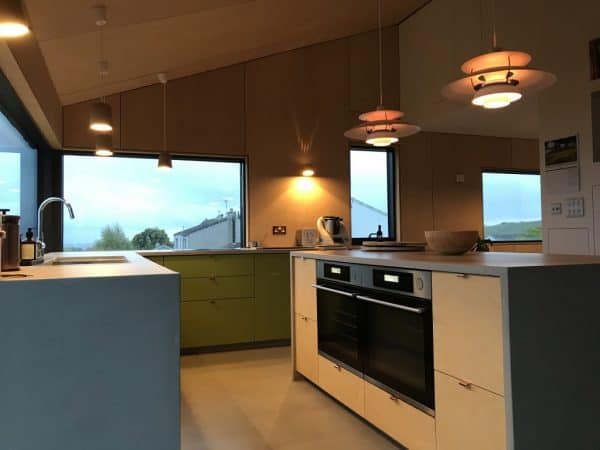 Bright kitchen with colourful cabinets, sleek appliances, and scenic view, showcasing innovative architectural design.