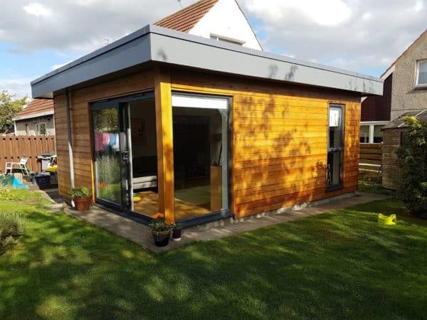 Garden room with wooden cladding, large glass sliding doors, and contemporary flat roof. Perfect outdoor workspace or studio.