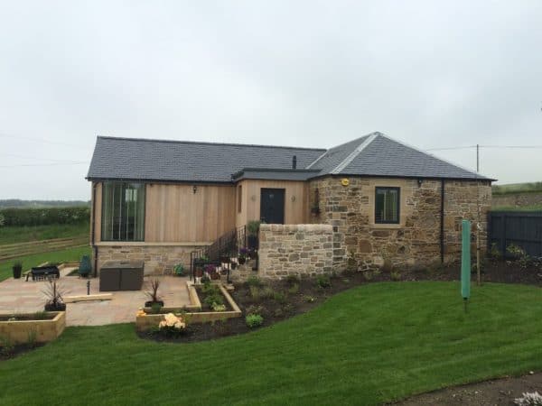 Charming rural house featuring stone and timber exterior with landscaped garden and outdoor patio.