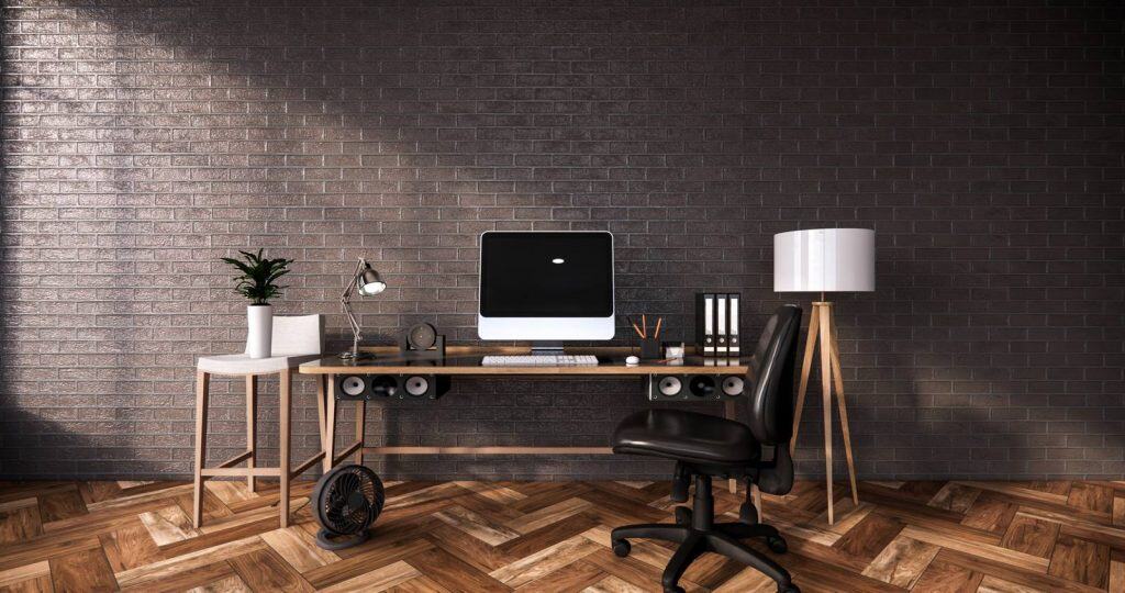 Bright home workspace featuring a sleek computer setup, stylish decor, and warm wooden flooring for productivity and comfort.