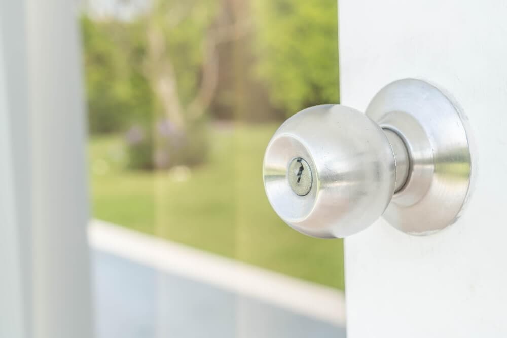 Secure metallic door knob with lock on glass door in modern architecture.