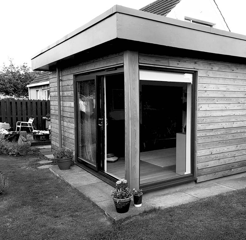 Elegant timber garden room with large sliding glass doors for seamless indoor-outdoor living.