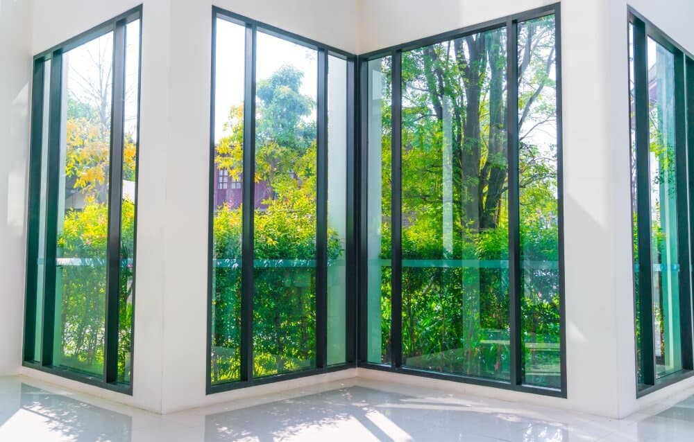 Elegant glass corner windows showcasing lush greenery outside.