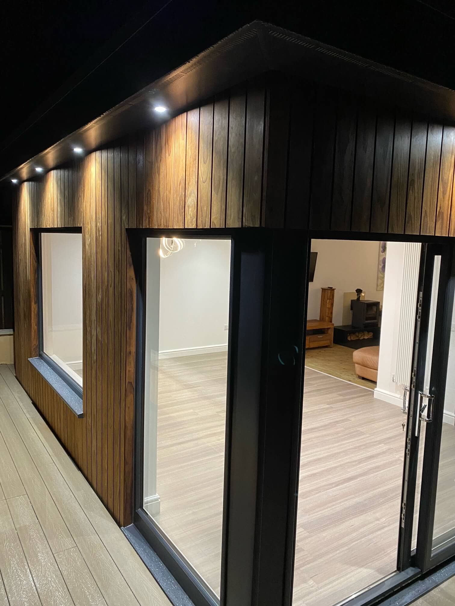 Stylish garden room with wooden cladding, glass doors, and modern design, perfect for outdoor living.