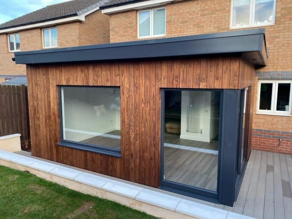 Highly functional outdoor space with timber-clad walls, large windows, and a sliding door for seamless indoor-outdoor living.