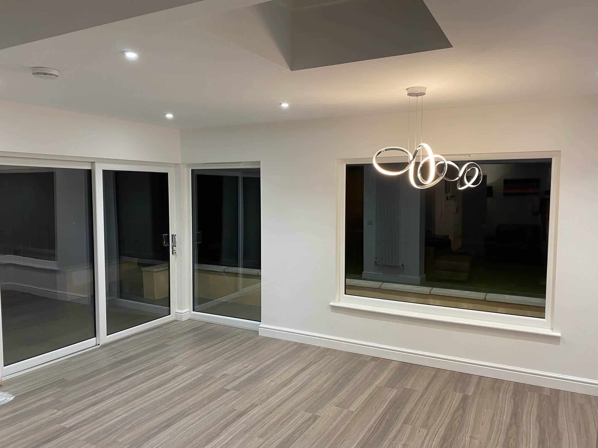 Bright contemporary interior with sliding glass doors, stylish pendant light, and wood-effect flooring.