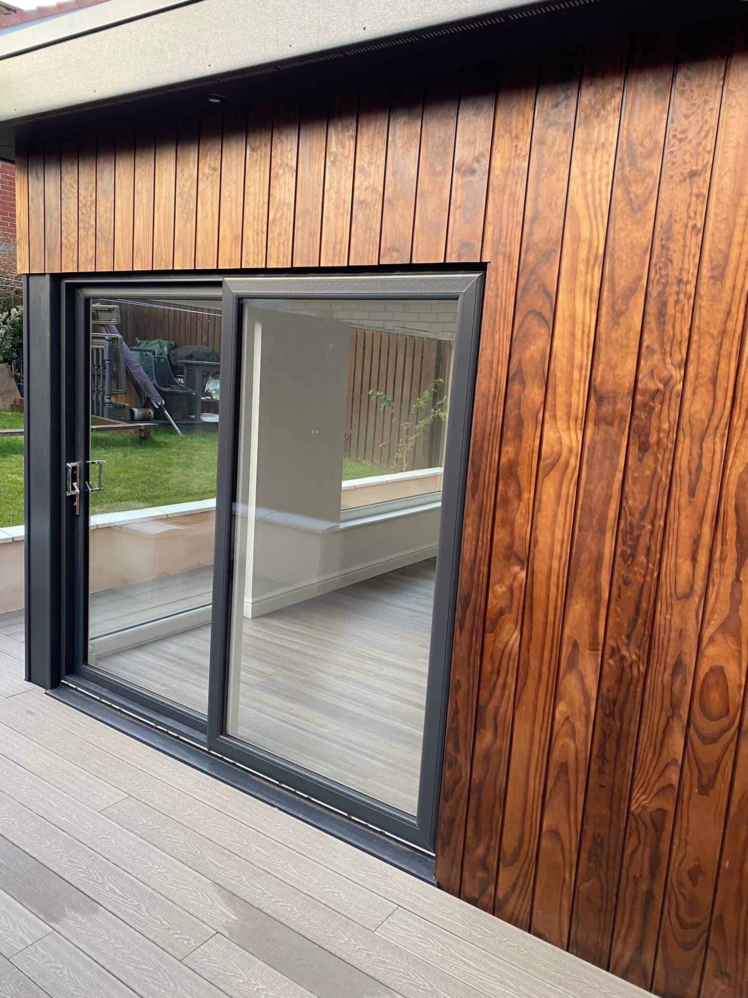 High-quality aluminium sliding door with black frame, installed in a modern home featuring timber cladding.