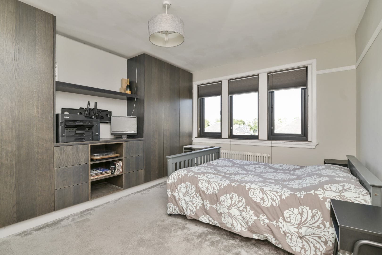 Contemporary bedroom with wooden built-in storage and large windows for natural light.