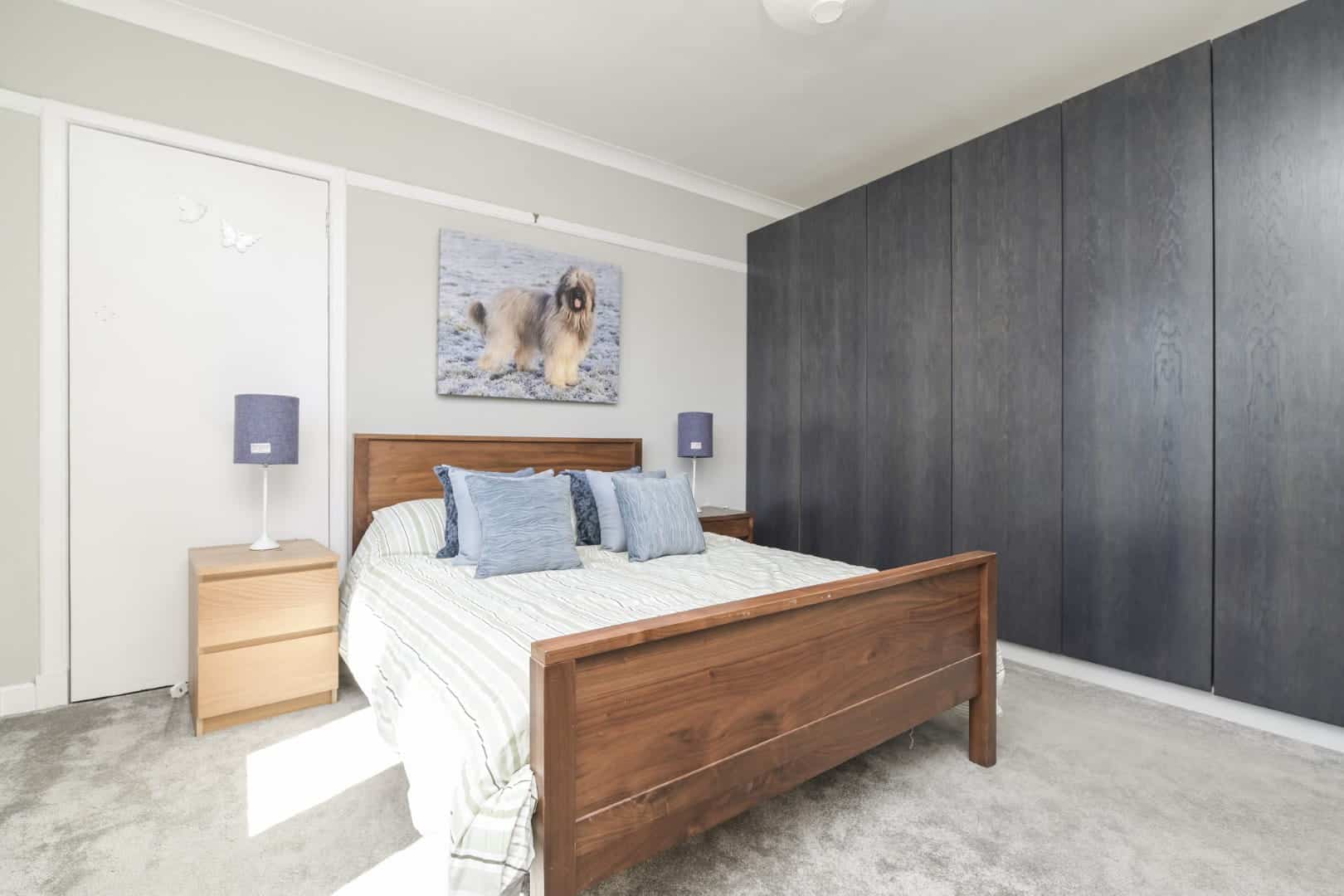 Bright bedroom with wooden bed, grey closet, and modern decor in contemporary home architecture.