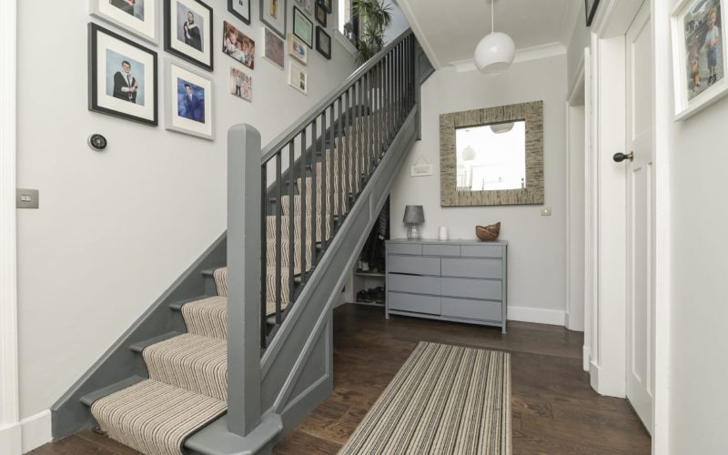 Stylish staircase with striped carpet runner leads to upper floor in contemporary home.