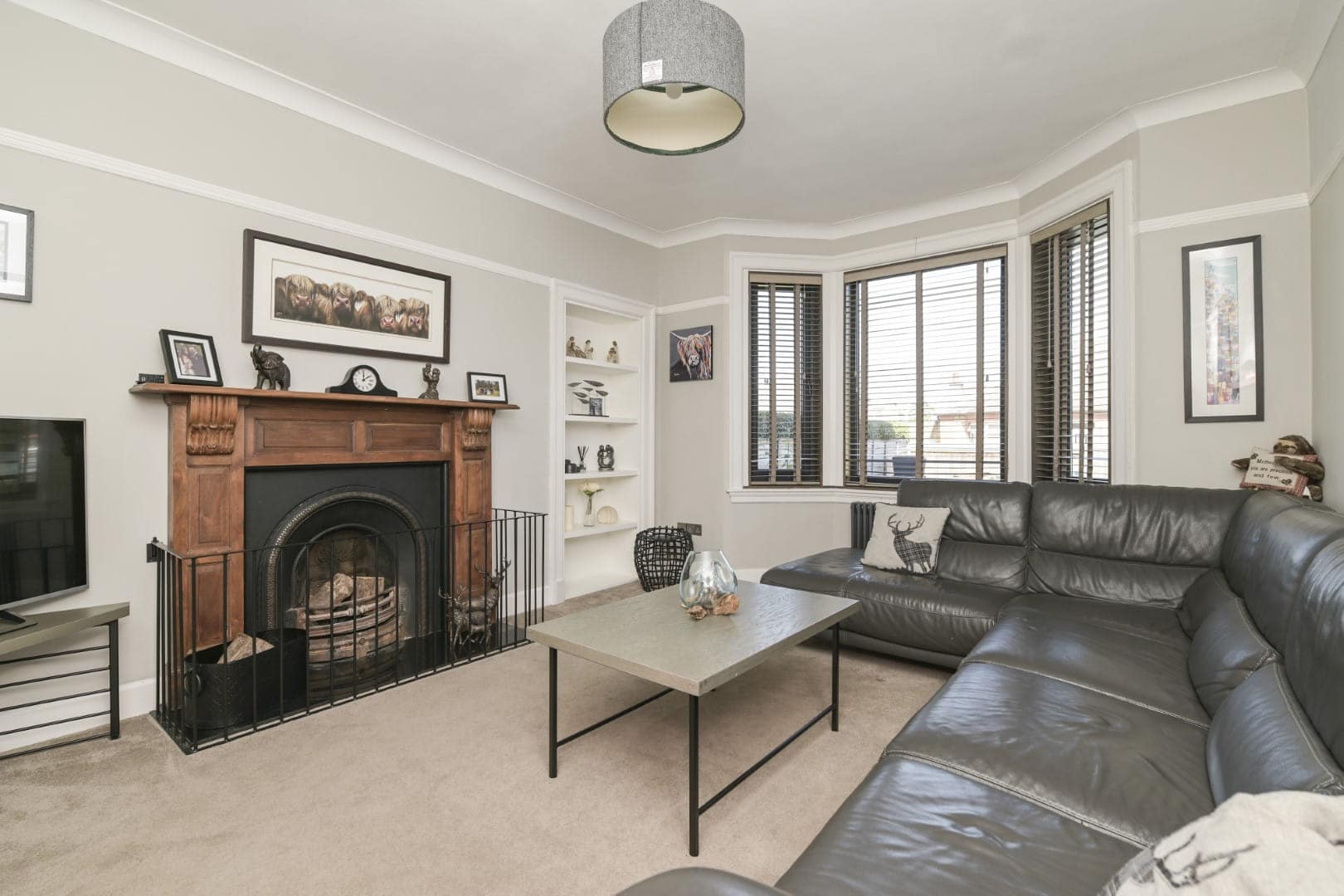 Elegant living room with fireplace, bay windows, leather sofa, and contemporary decor.