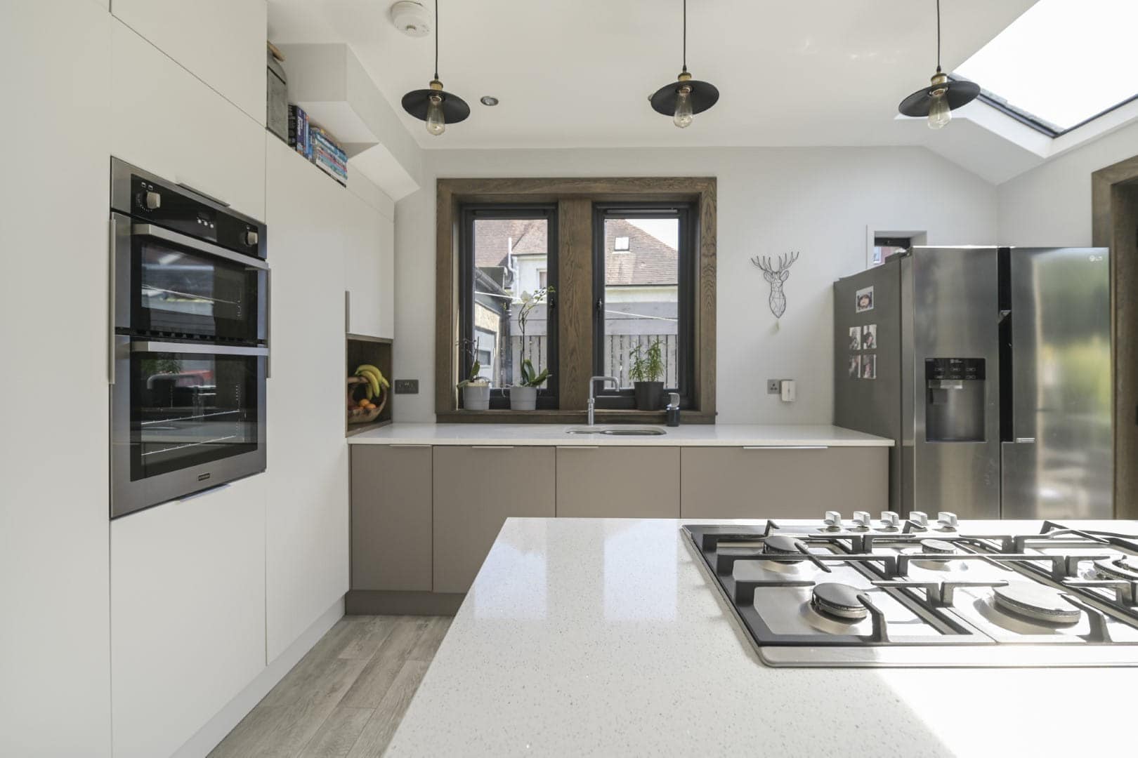 Bright, contemporary kitchen with integrated appliances, wooden window frame, and skylight for a spacious feel.
