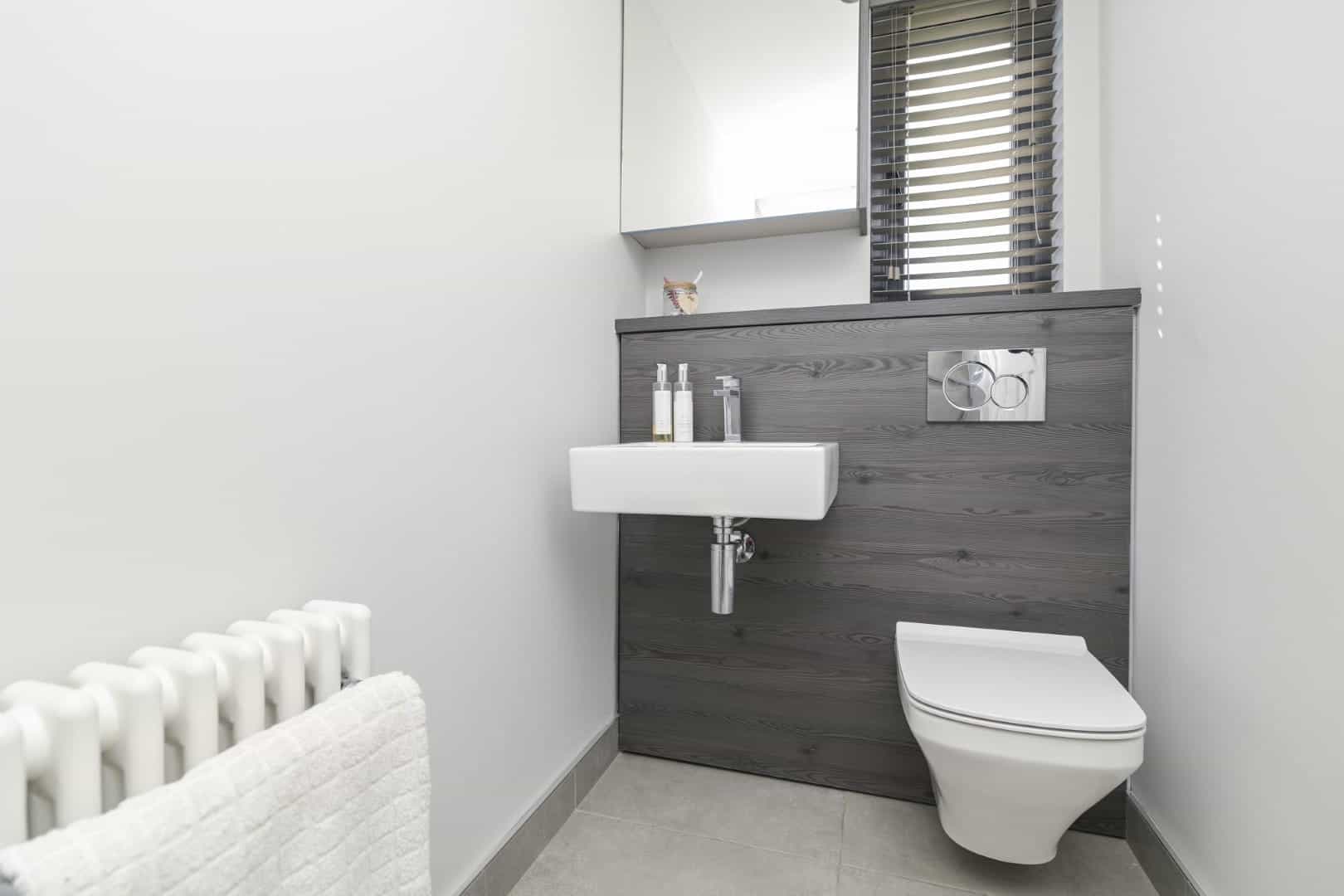 Clean, contemporary bathroom with sleek white fixtures and natural wood accent wall.