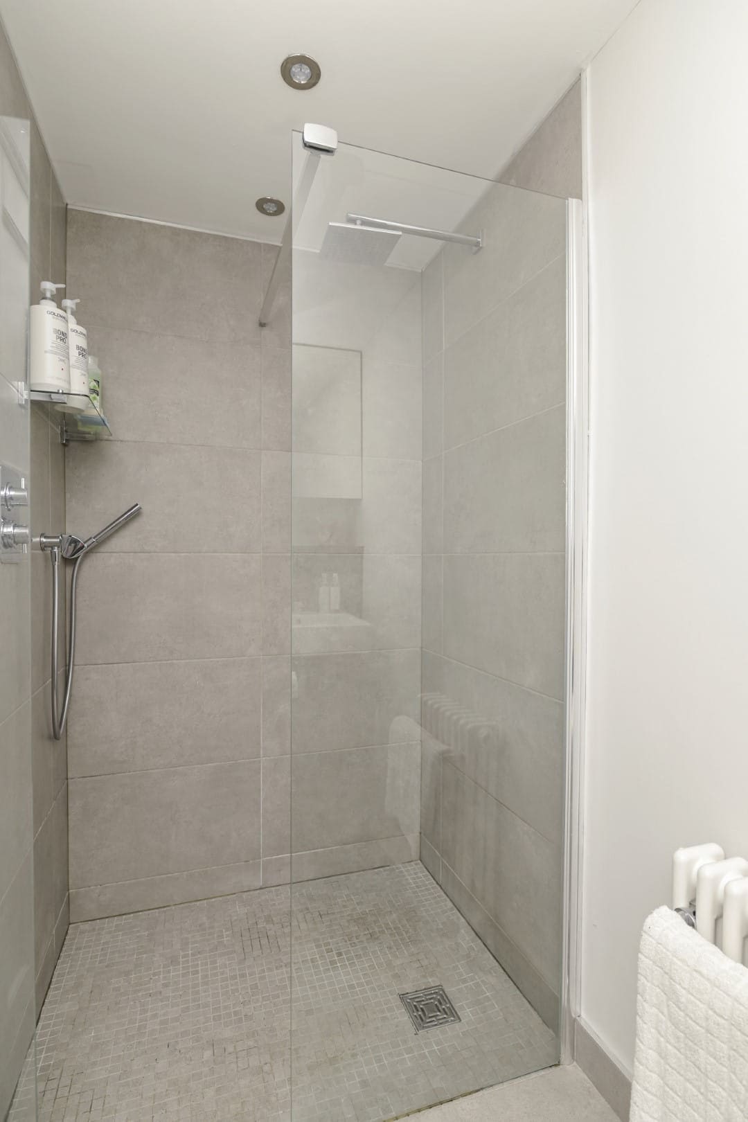 Elegant bathroom shower design with beige wall tiles and chrome fixtures.