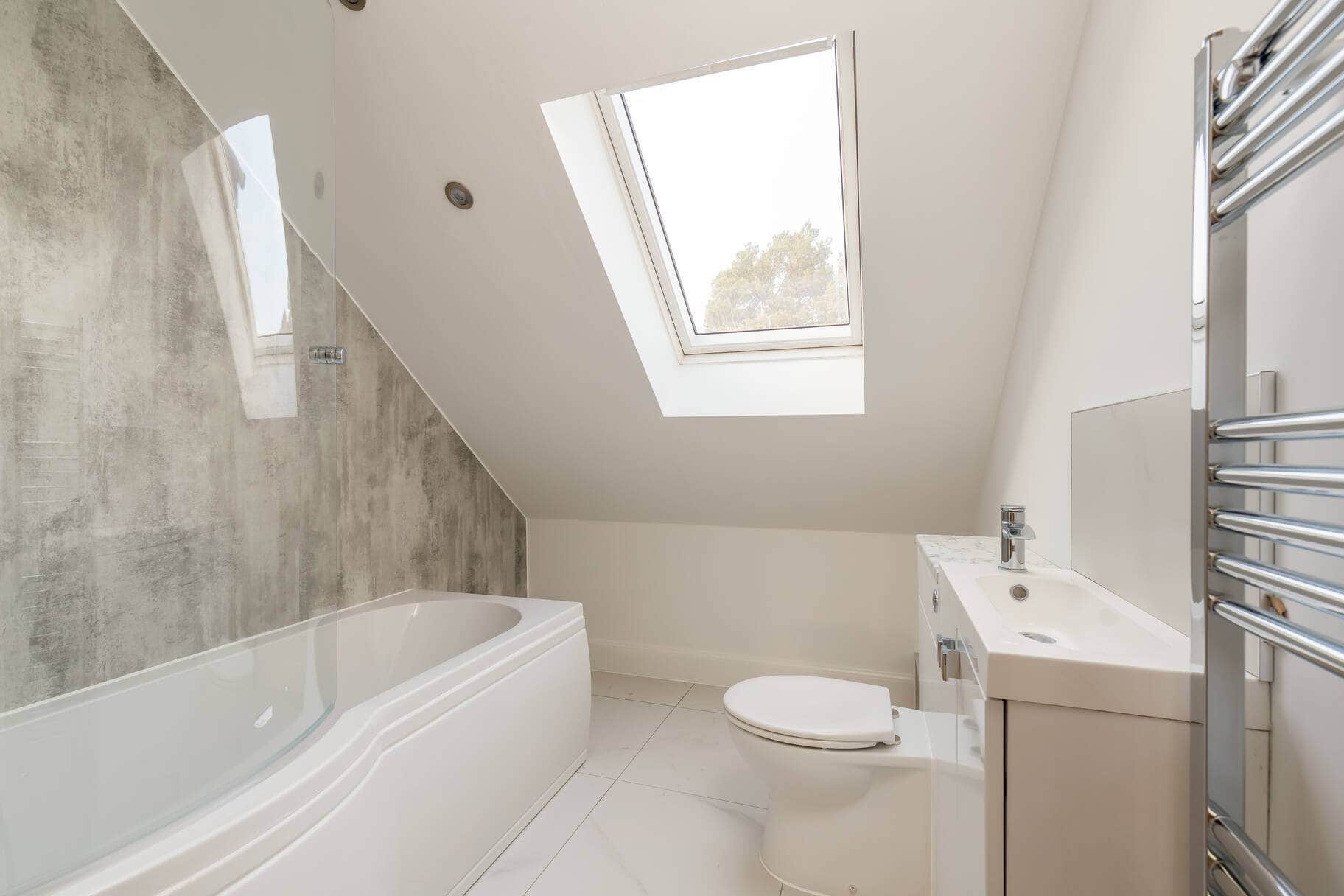 Bright bathroom featuring a skylight, sleek white fixtures, and contemporary style.