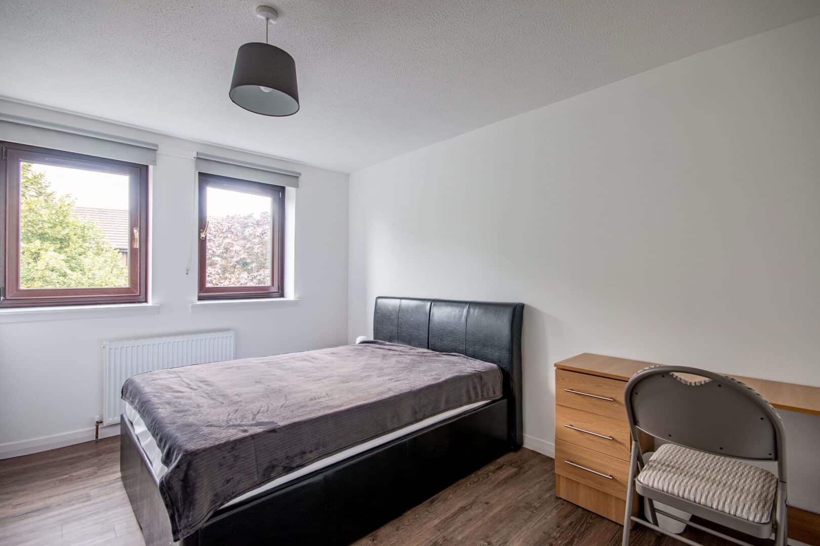 Bright modern bedroom featuring double-glazed windows, minimalist decor, and natural lighting in a residential property.