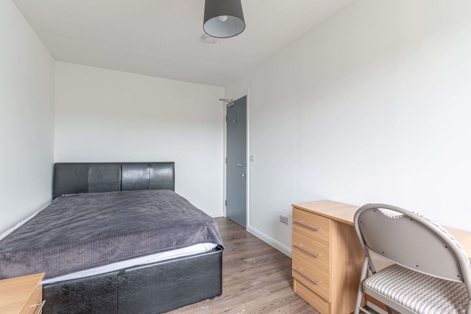 Spacious bedroom with contemporary minimalist design, including bed, desk, and chair.