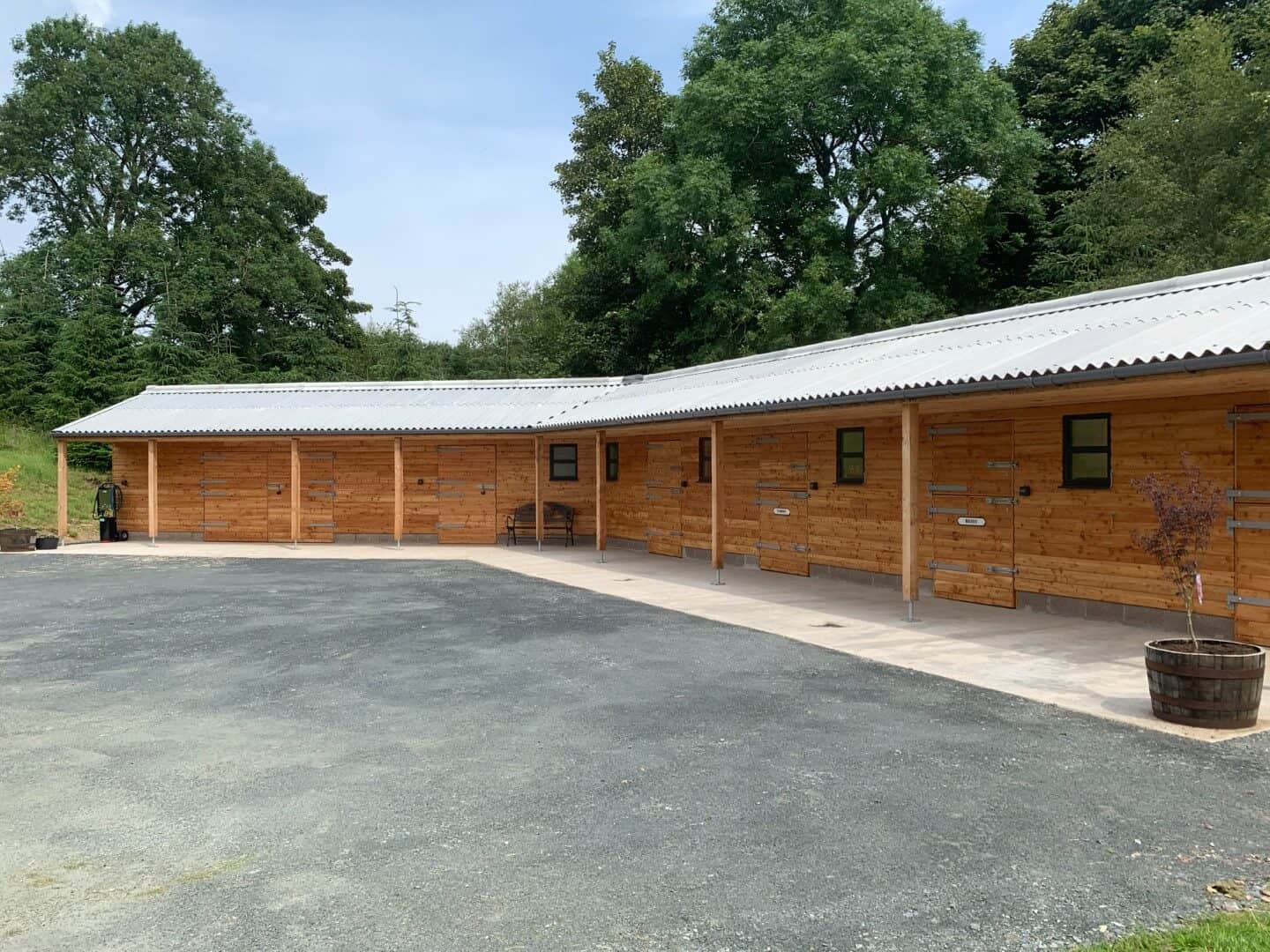 Sustainable timber stable building with metal roof, designed by ABC Architecture, situated in lush green surroundings.