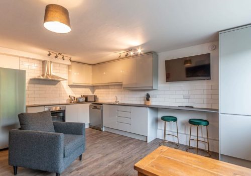 Bright open-plan kitchen with sleek cabinetry, white tiles, and a cosy seating area for modern homes.