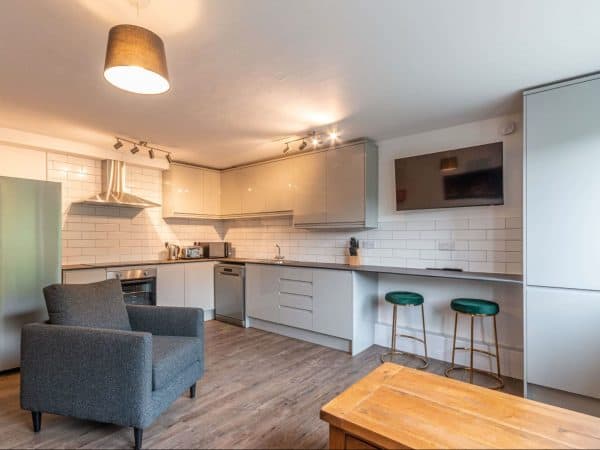 Bright open-plan kitchen with sleek cabinetry, white tiles, and a cosy seating area for modern homes.