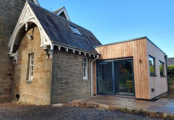 Modern wooden house extension with large glass doors.