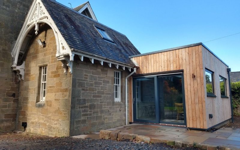 Modern wooden house extension with large glass doors.