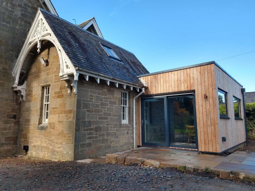 Modern wooden house extension with large glass doors.