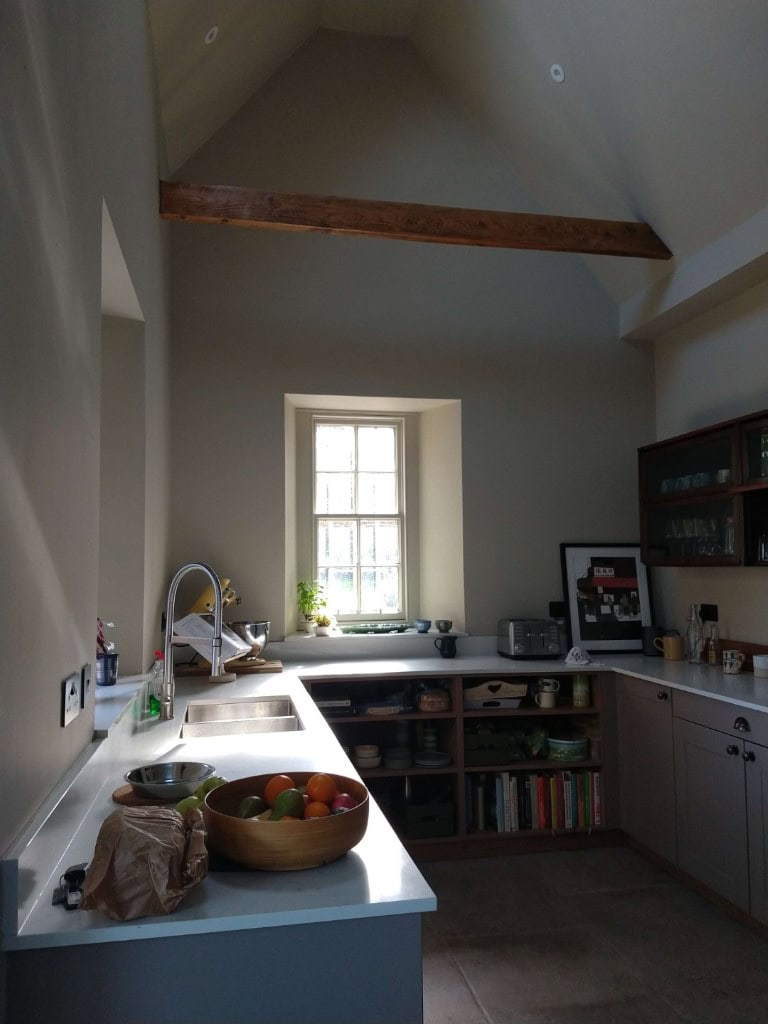 Bright kitchen interior with a large window, wooden beams, and modern appliances, designed by ABC Architecture.