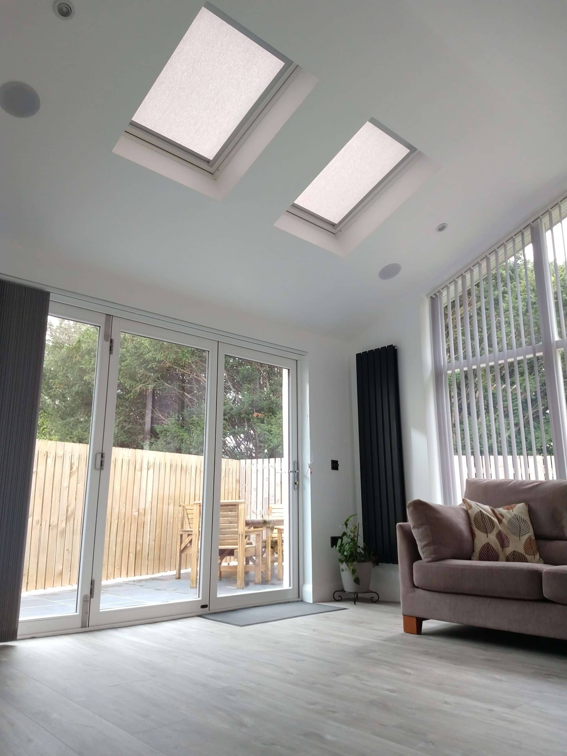 Bright modern living room with skylights, floor-to-ceiling windows, and outdoor patio.