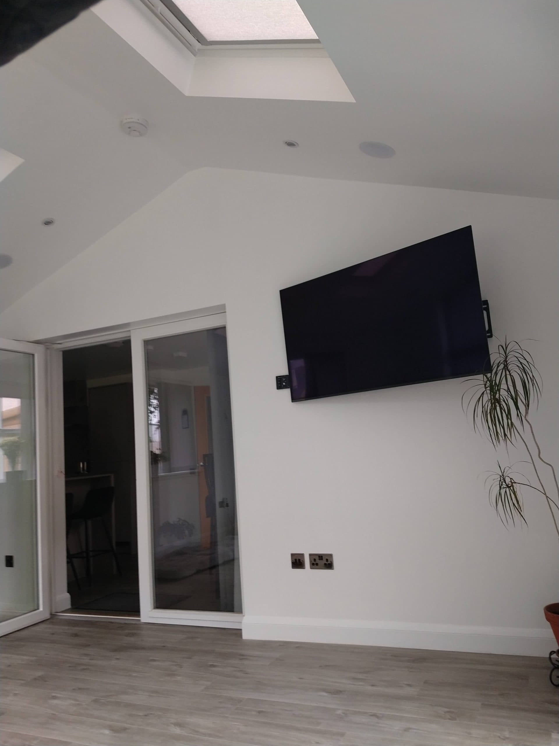 Contemporary home living room with minimalist decor, flat-screen TV, and sliding glass doors.