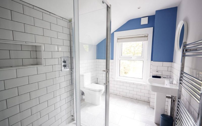 Bright, contemporary bathroom with white subway tiles, blue accent wall, and modern fixtures.