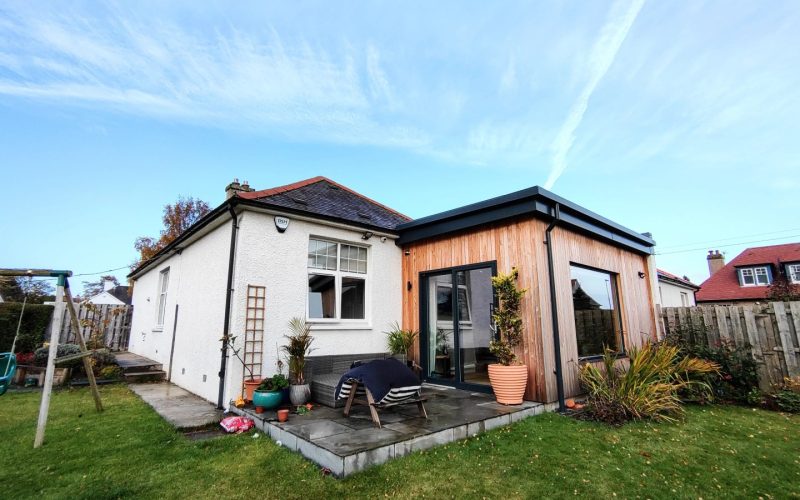 Contemporary garden room extension with timber exterior and large sliding glass doors, designed for outdoor living.