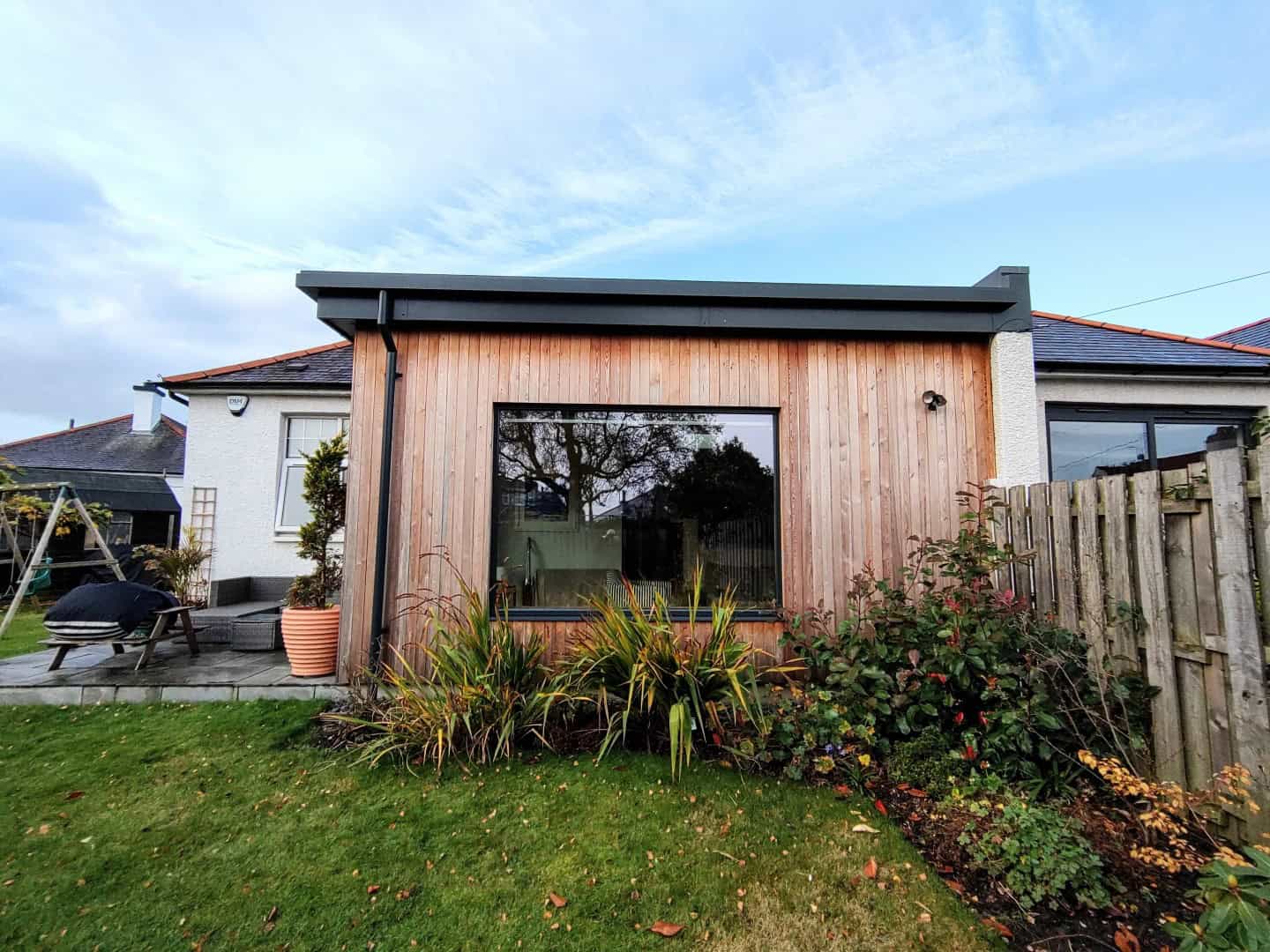 Contemporary garden room with wooden facade and expansive glass window for outdoor living.