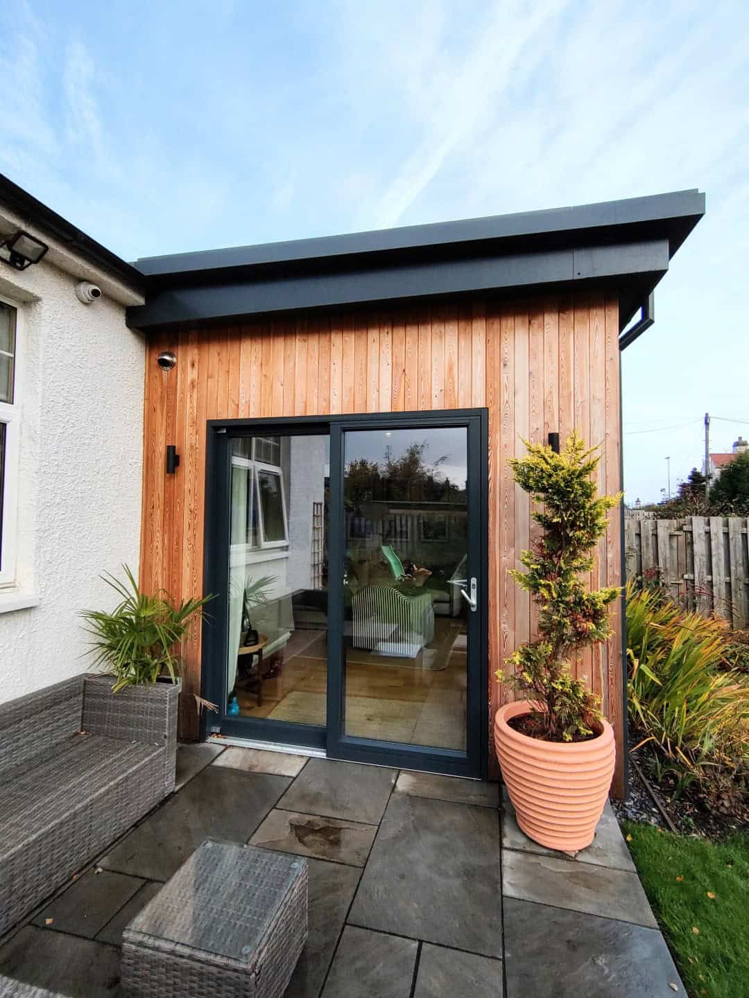 Modern garden room with wooden exterior and large glass doors, ideal for outdoor entertaining and relaxation.