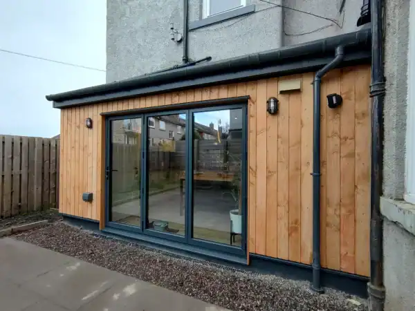 Contemporary garden extension with timber facade, large glass doors, and external lighting for modern outdoor spaces.
