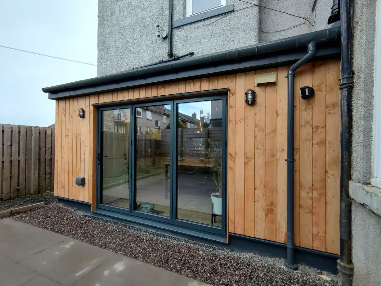 Contemporary garden extension with timber facade, large glass doors, and external lighting for modern outdoor spaces.