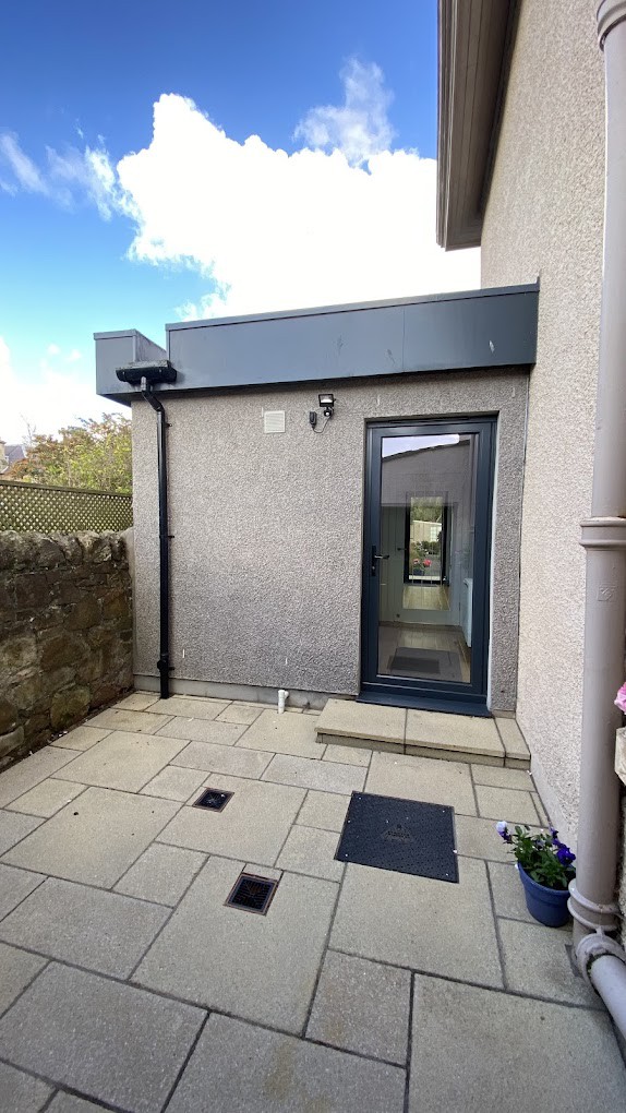 Contemporary house extension design featuring a glass door, outdoor patio, and clean paving, showcasing innovative architectural solutions.