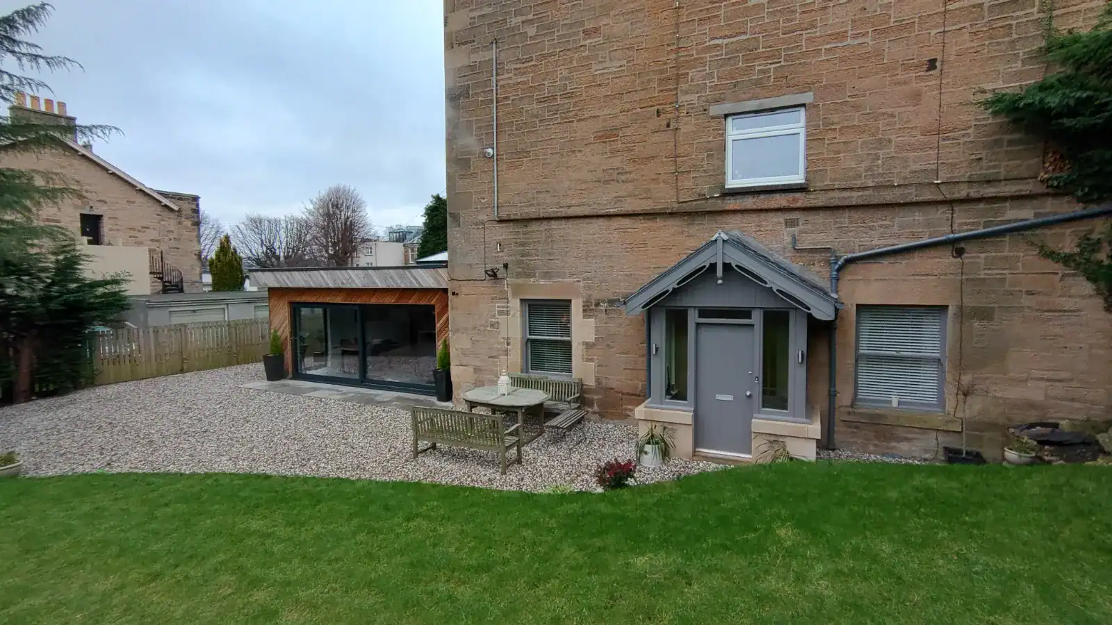 Contemporary home extension featuring large sliding doors, garden patio, and outdoor seating area.