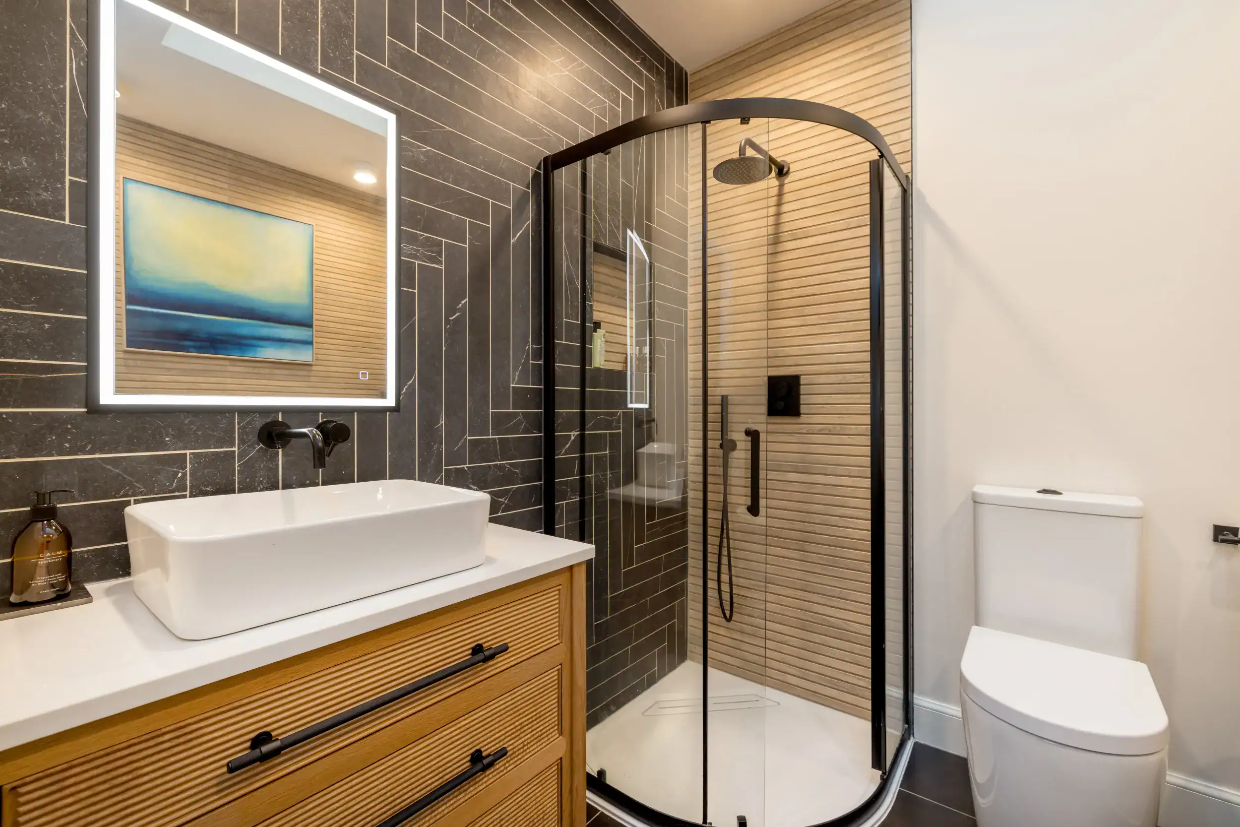 Contemporary bathroom featuring black tile walls, wooden accents, and a stylish glass shower.