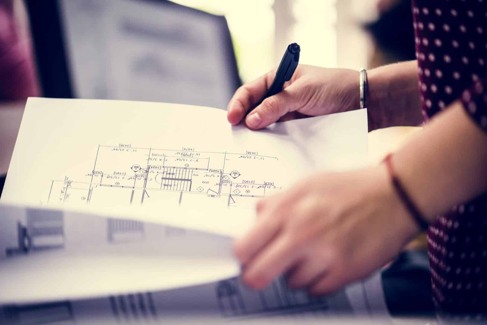 A person reviewing detailed architectural blueprints, focusing on building design and construction plans.
