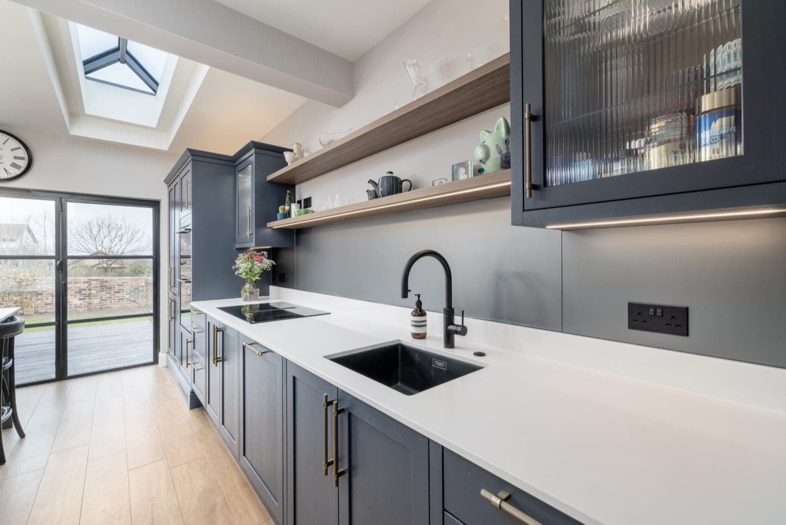 Stylish kitchen featuring navy blue cabinets, open shelves, and a sleek black sink for contemporary homes.