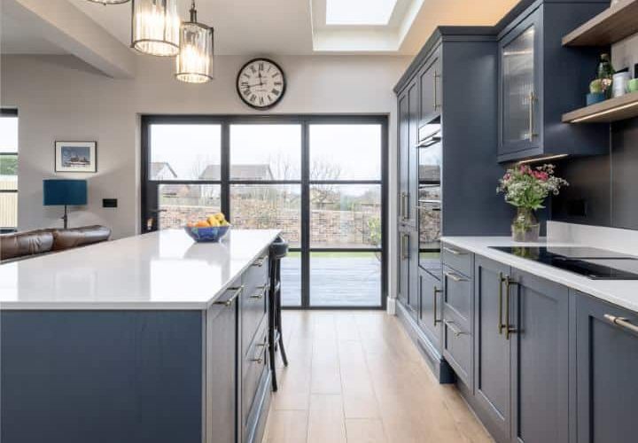 Bright contemporary kitchen with navy blue cabinets, skylight, and wooden flooring.