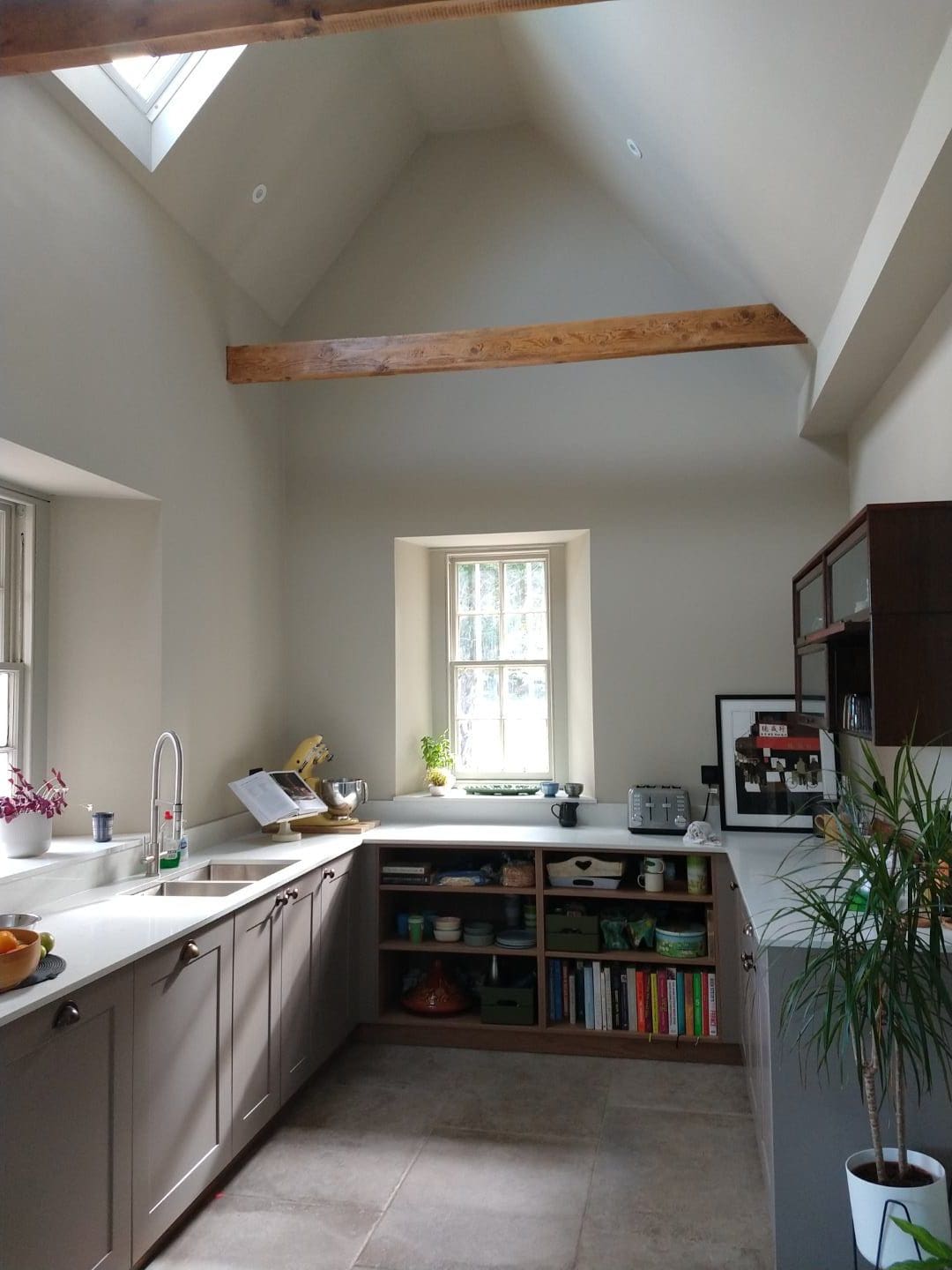 Bright kitchen with skylight and large window, wooden beams, contemporary cabinetry, perfect for modern homes.