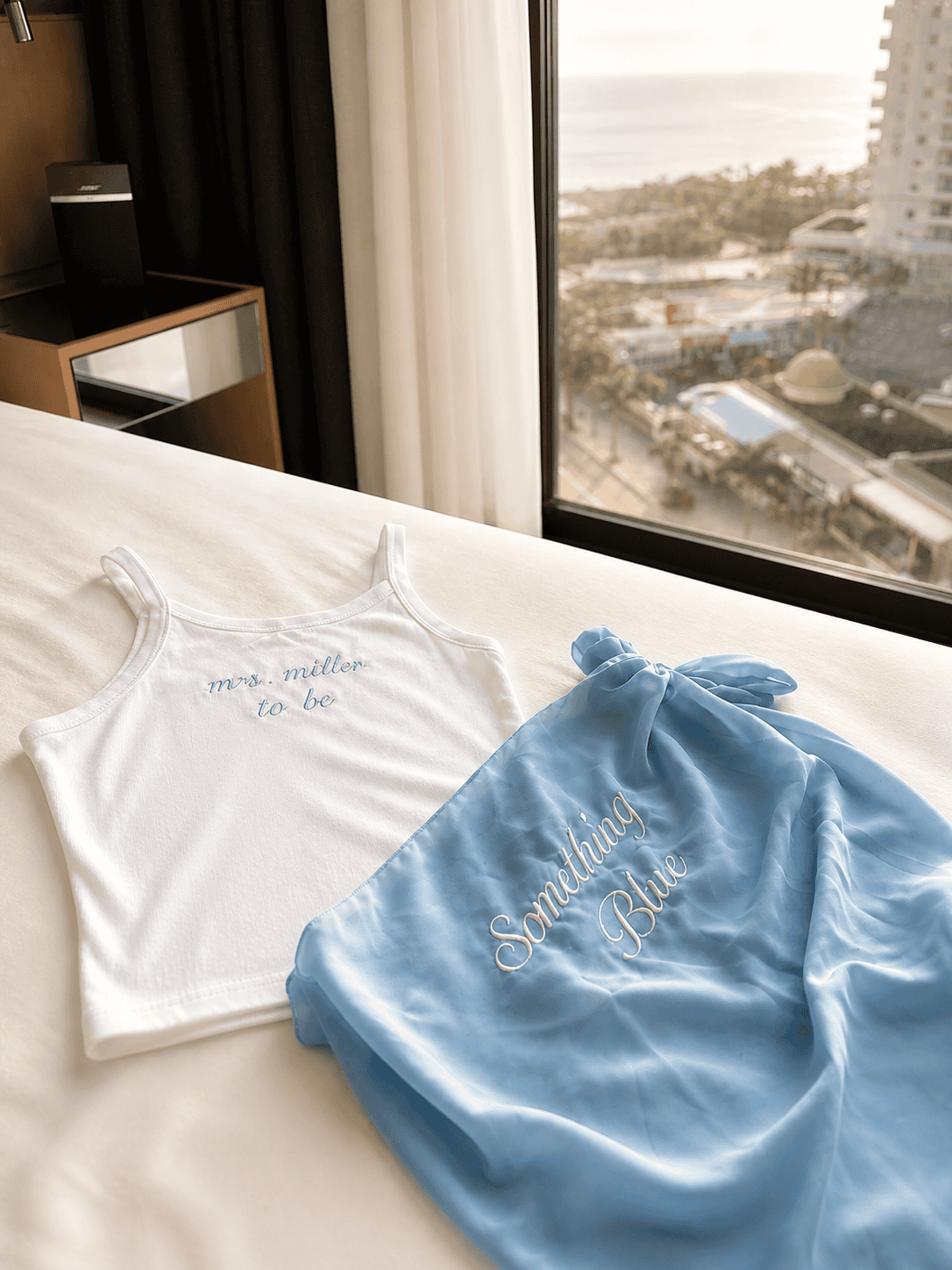 White sleepwear and blue embroidered bag with "Sommilina Blue" text near a window.