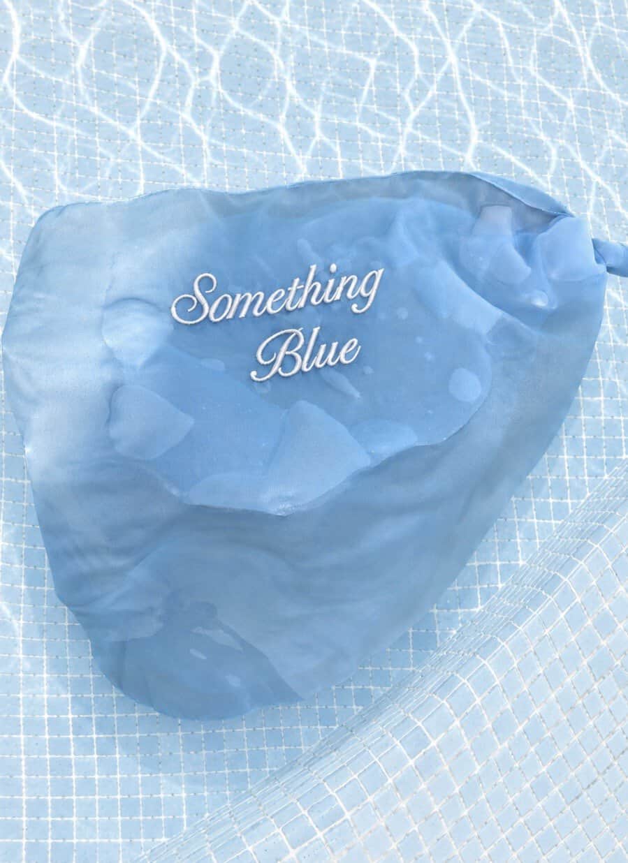 Embroidered heart with "Something Blue" text on a blue fabric background, perfect for wedding or rom.