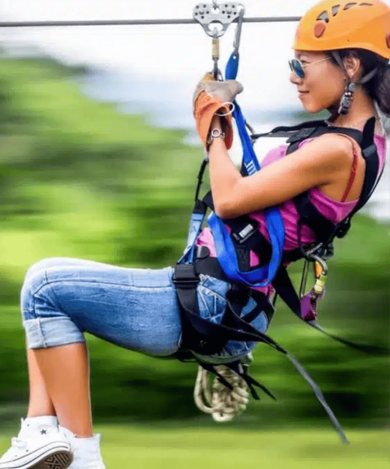 Punta Cana Young woman enjoying ziplining in Punta Cana wearing helmet and harness.