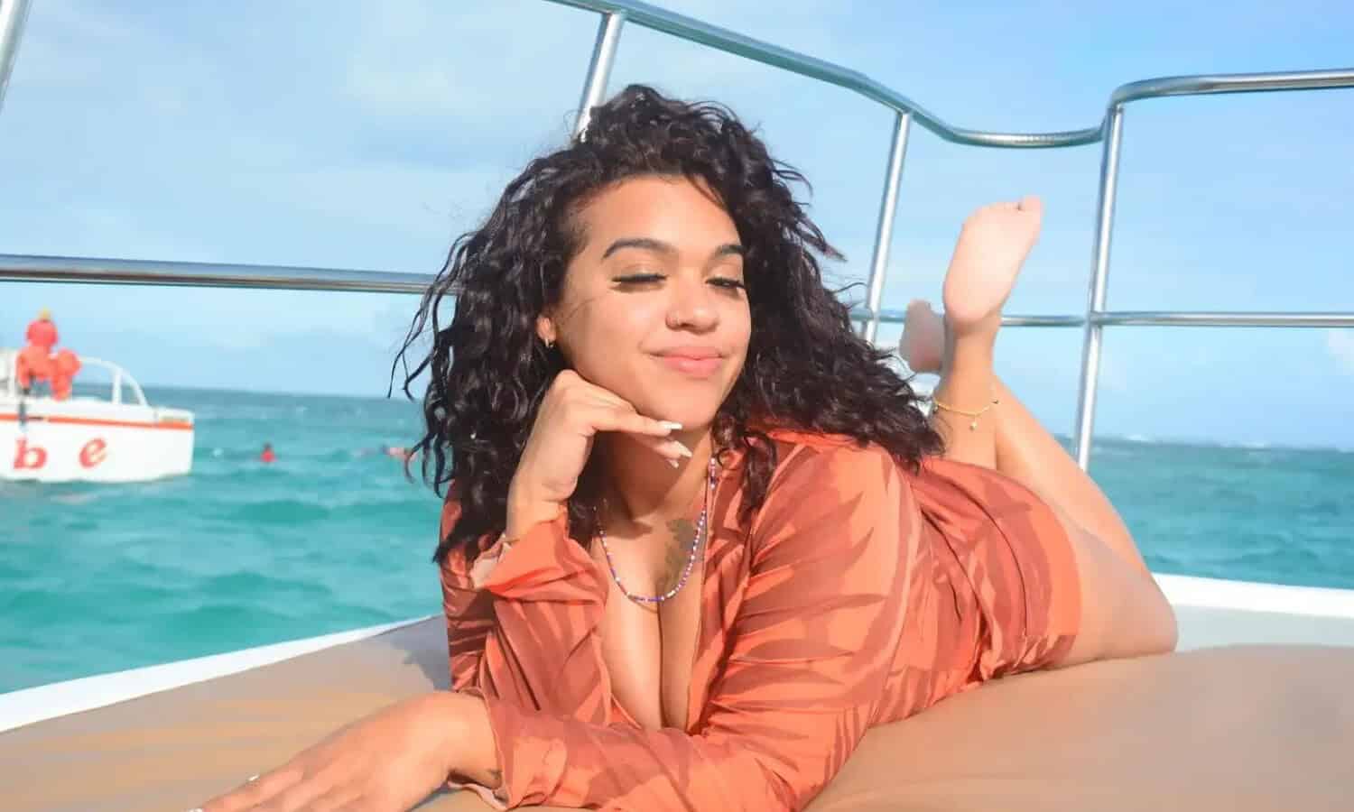 Punta Cana Relaxed woman lying on a boat in Punta Cana, Dominican Republic, with clear blue water and a boat in.