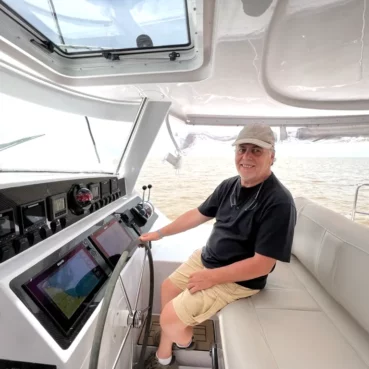 High-performance Antares Catamaran captain steering navigation instruments on a modern boat.
