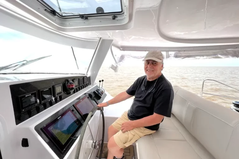 High-performance Antares Catamaran captain steering navigation instruments on a modern boat.